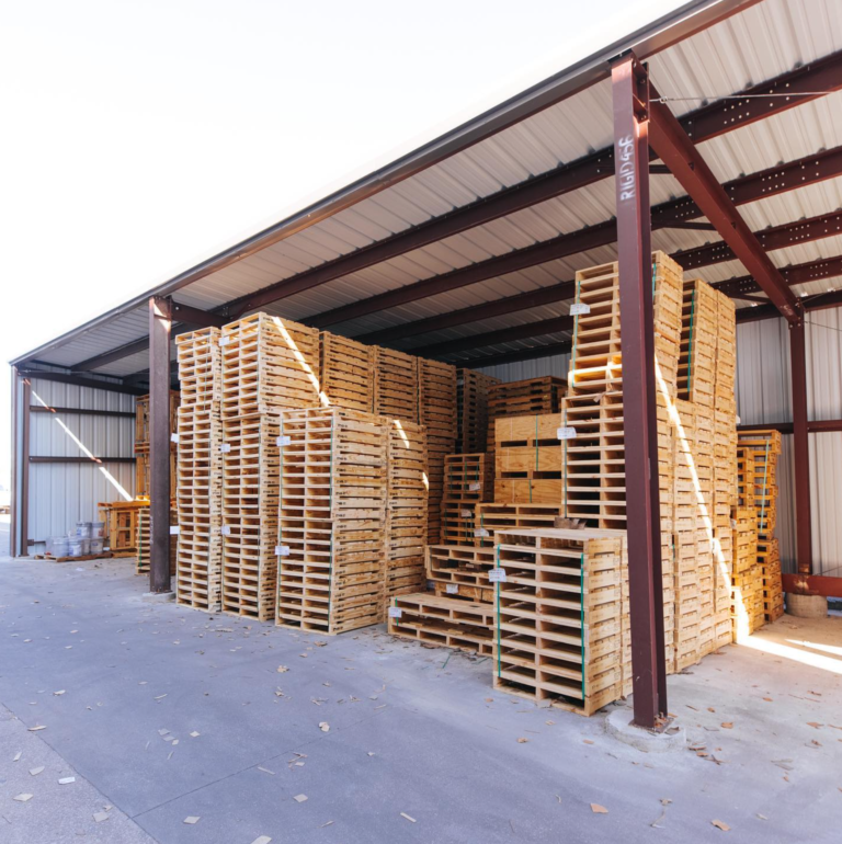 GPC Texas warehouse filled with wooden pallets has a sign that says ' pallets ' on it.